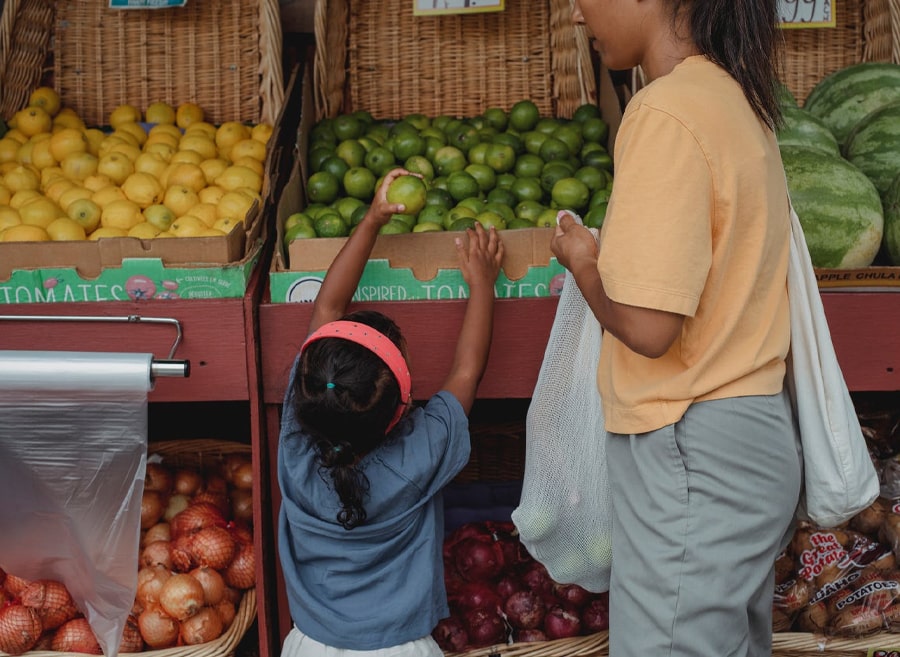 mother and daughter buying fruits in the local market