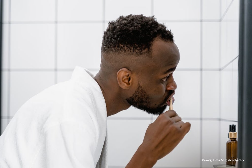 man brushing his teeth using bamboo toothbrush
