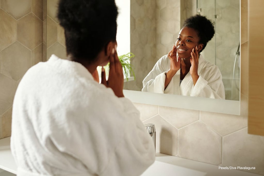 woman looking at the mirror while touching her face