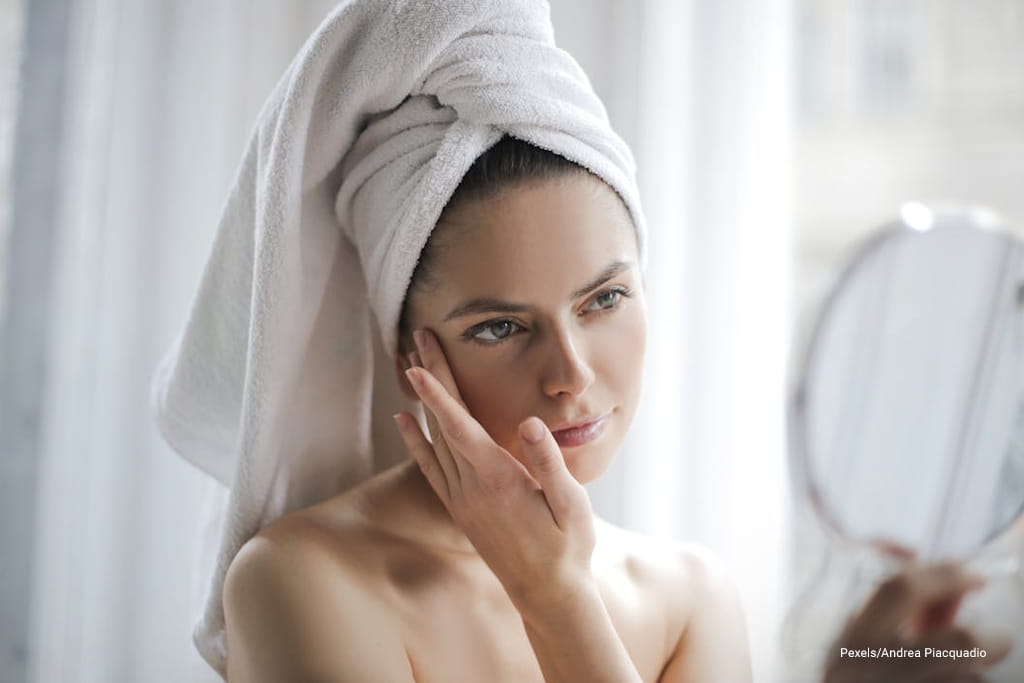 woman touching her face while looking her self at the mirror