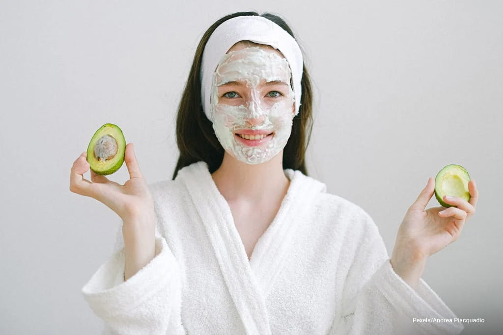 woman holding slice avocado with facial wash on
